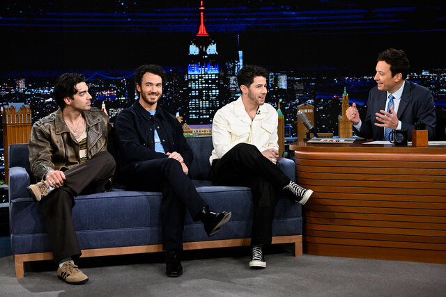 Jonas Brothers seated on the couch of the Tonight Show with Jimmy Fallon