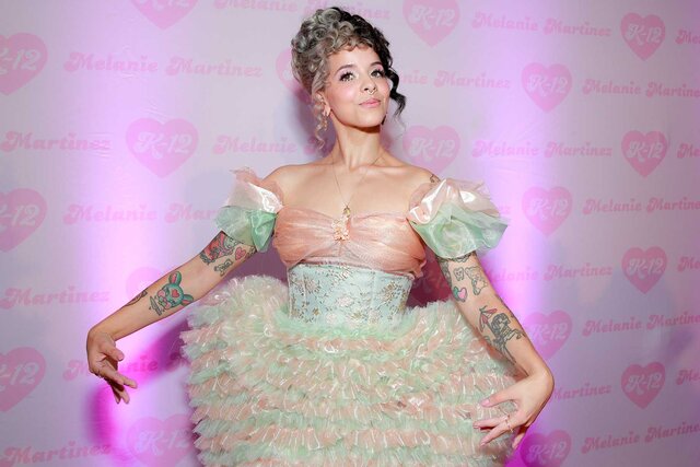 Melanie Martinez posing on the carpet wearing a green and pink dress at the Melanie Martinez K-12 film premiere.