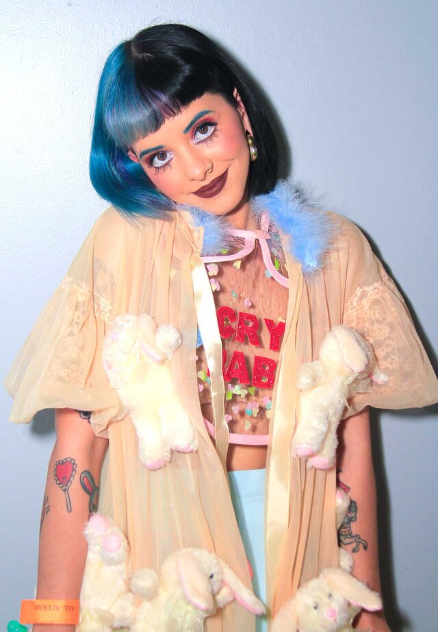 Melanie Martinez smiling and posing for the camera backstage at an event.