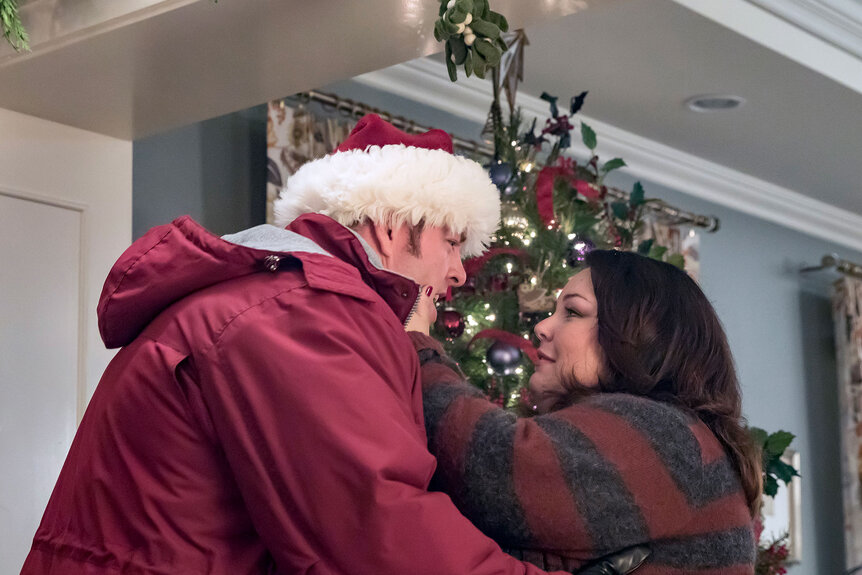 Kate and Toby hugging in their home with a christmas tree in the background