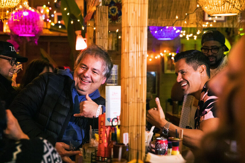 Jay Hernandez laughing with another man at the bar