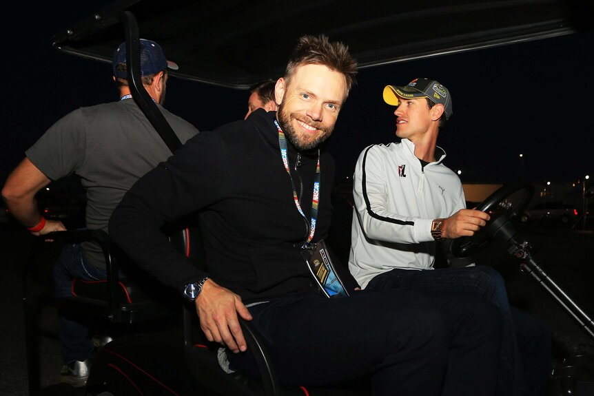 Joel Mchale in a golf cart with friends.