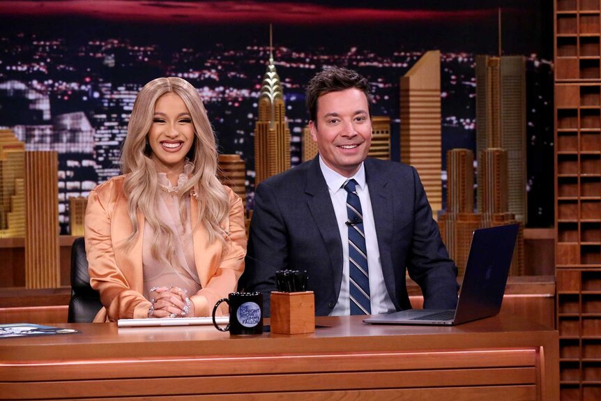 Cardi B sitting with Jimmy Fallon during The Tonight Show.
