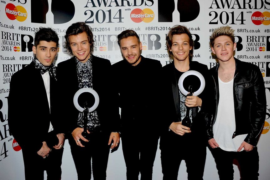 Zayn Malik, Harry Styles, Liam Payne, Louis Tomlinson and Niall Horan posing for photos holding awards.