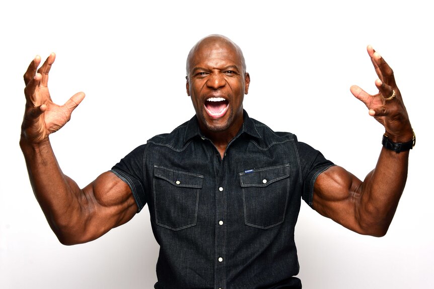 Terry Crews posing with his hands up.