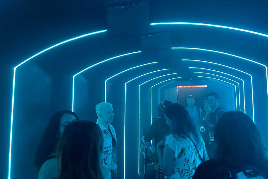 Fans in a dark hallway with blue neon lights at San Diego Comic-Con 2023