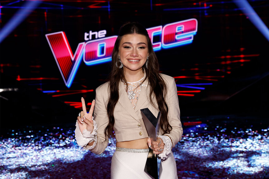 Gina Miles on The Voice stage holding her winner's trophy