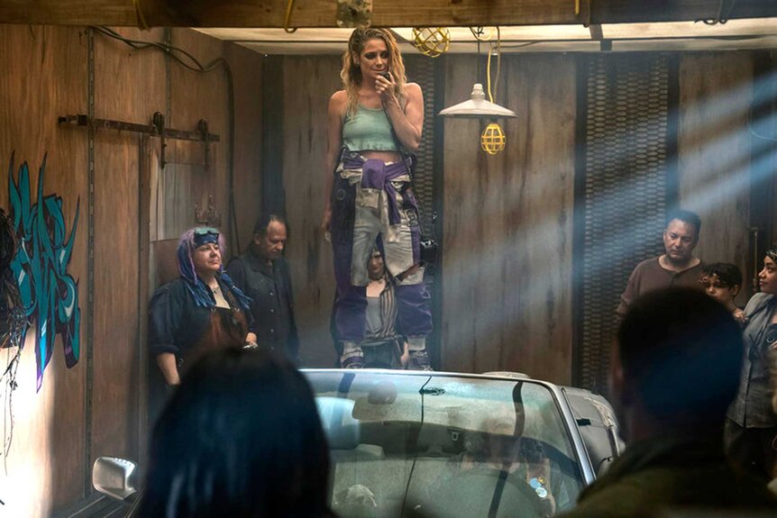 Character Miranda appears on top of a table during a scene in Twisted Metal.