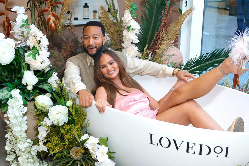 John Legend and Chrissy Teigen sitting in a bath tub together at an event.