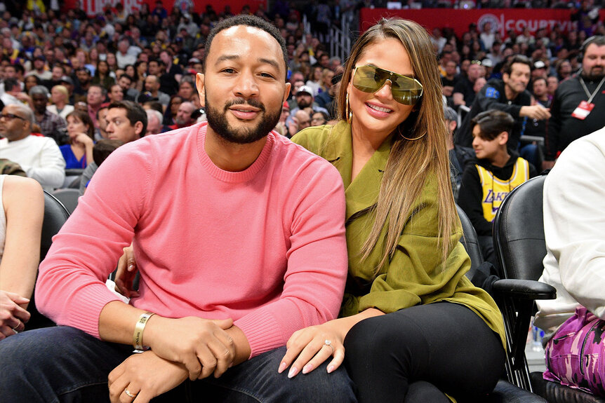 John Legend and Chrissy Teigen front row at a basketball game