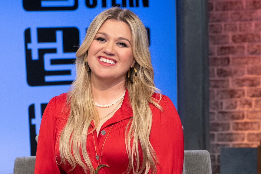 Kelly Clarkson smiles while looking into the camera