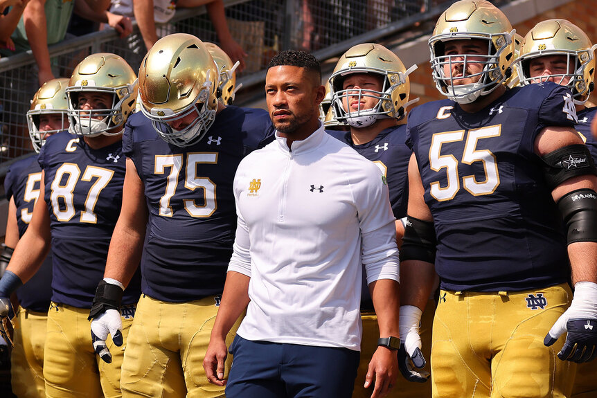 Head coach Marcus Freeman and team take the field