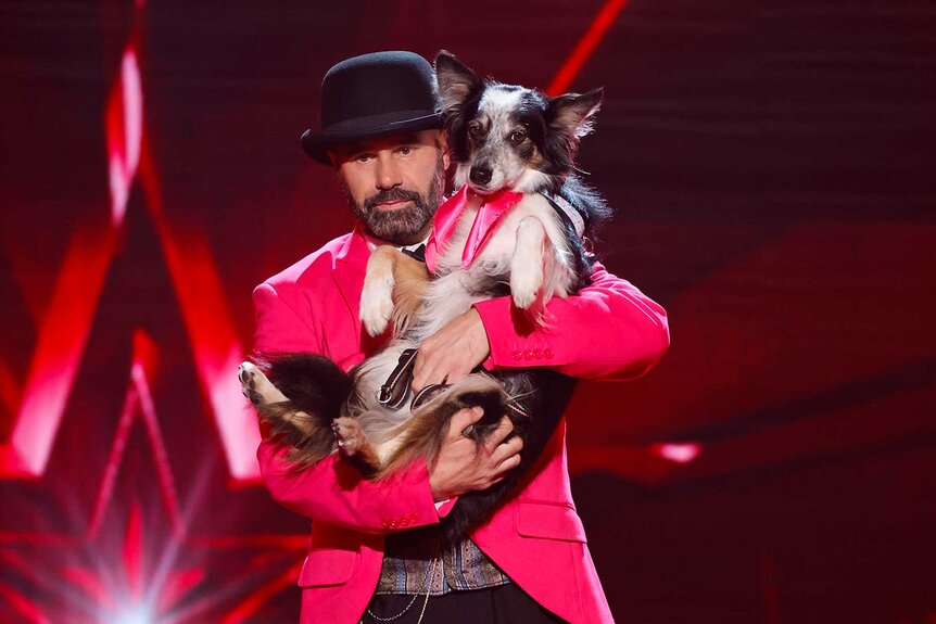 Adrian Stoica holding his dog Hurricane close on stage.