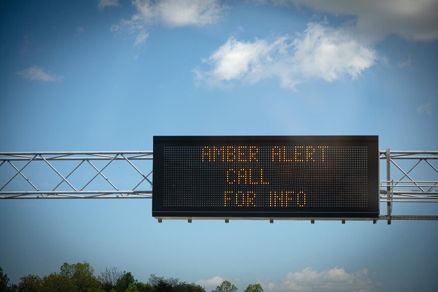 A sign above a highway that says amber alert call for info