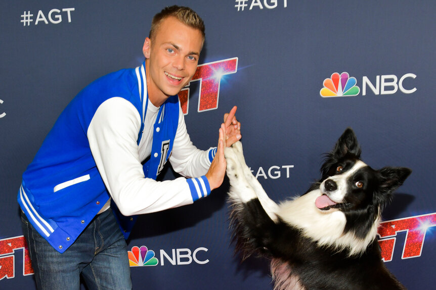 Lukas and his dog Falco high five while smiling on the red carpet