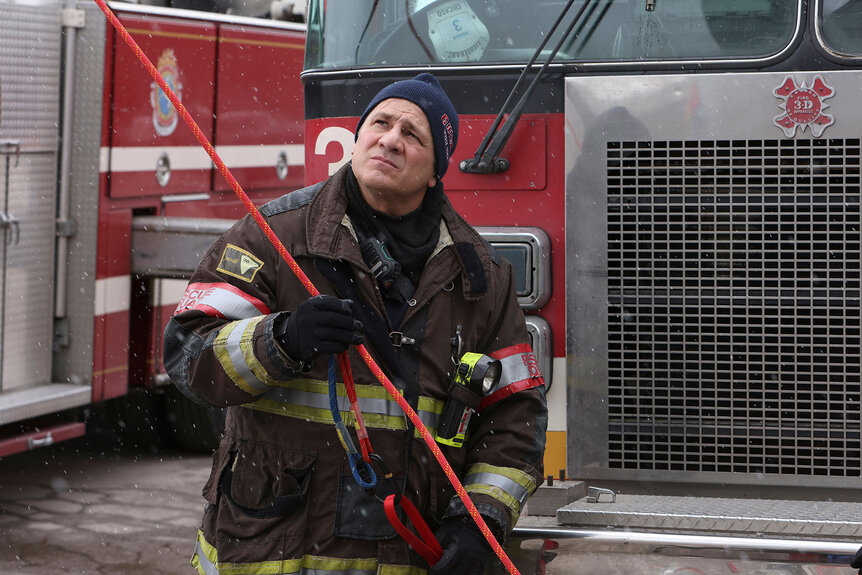 Firefighter Tony on Chicago Fire episode 1121 pulling a rope in front of a firetruck