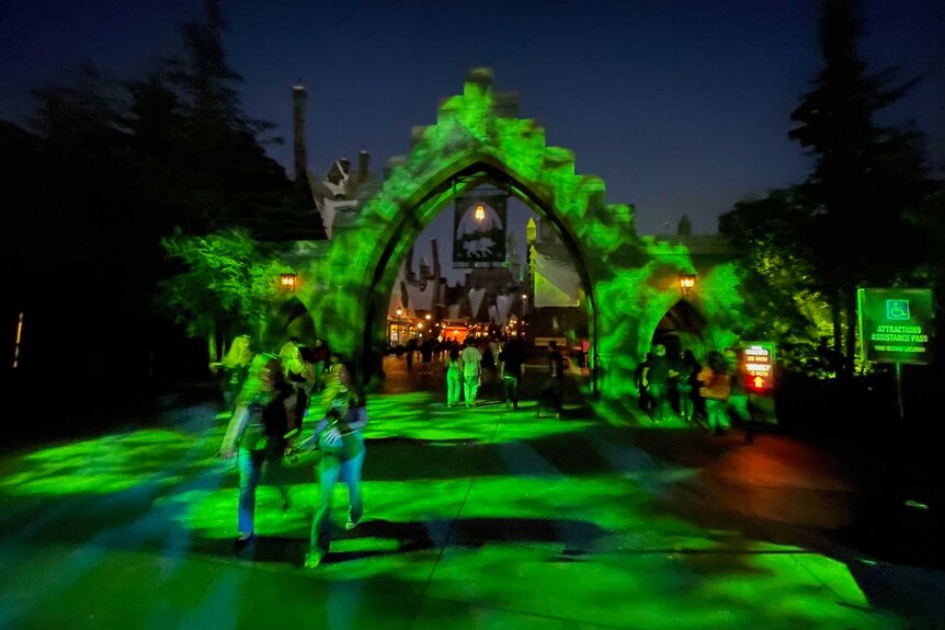 Guests walking down a dark pathway that's lit up in a green light.