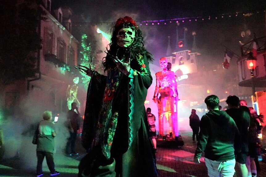 A scare actor dressed as a skeleton creature in the middle of a crowd at Halloween Horror Nights.