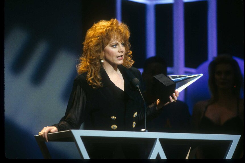 Reba McEntire at a podium on stage accepting an award at the American Music Awards in 1993.
