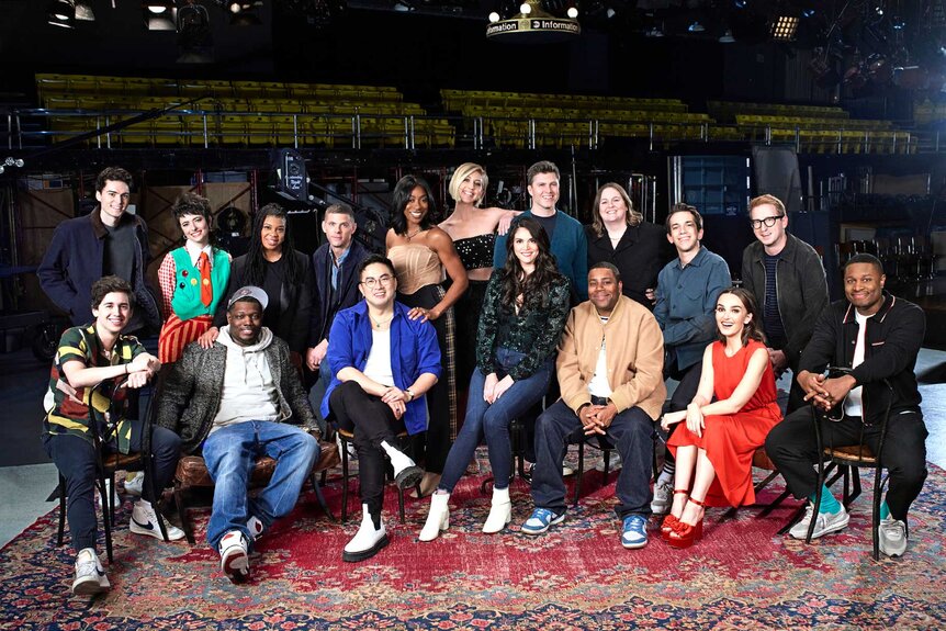 The cast of Saturday Night Live Season 48 posing for a photo while sitting on a red rug.