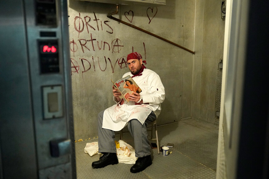 A chef sits reading a magazine in a freezer
