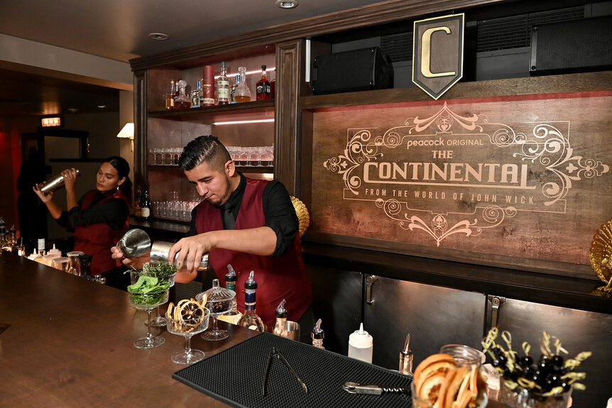 A bartender shakes a drink while another bartender pours a drink at the bar