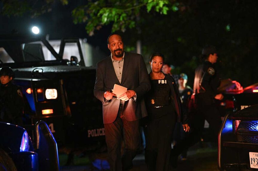 Alec Mercer and Marisa walking together throughout a scene of cop cars.
