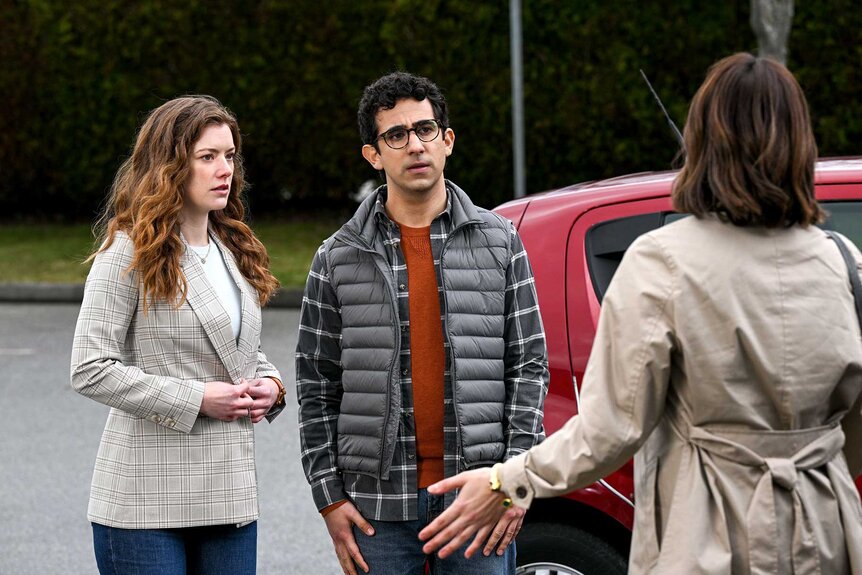 Phoebe and Rizwan standing next to each other while talking to a character outside.