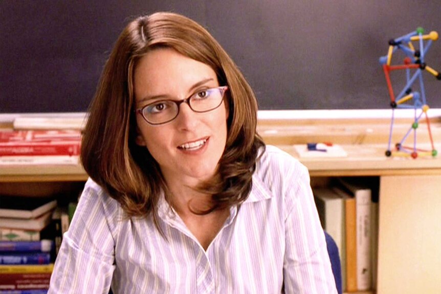 Ms. Sharon Norbury wearing a pink and white button down and glasses during a scene in Mean Girls.