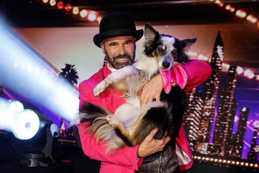 Adrian Stoica, wearing a pink suit, holds his Border Collie Hurricane.