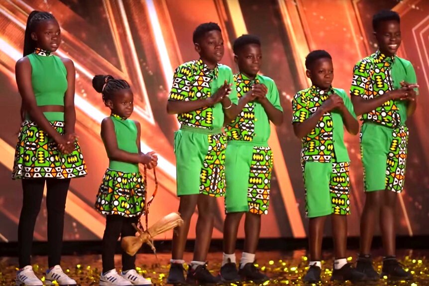 Dance group, Ghetto Kids, on stage wearing green outfits standing next to each other.