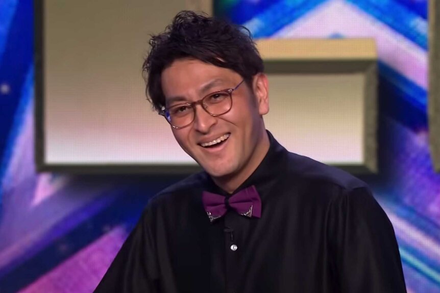 A close up of Ichikawa Koikuchi smiling and wearing a purple bow tie and black shirt.