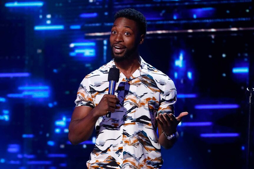 Preacher Lawson performing on stage with a microphone in his hand.