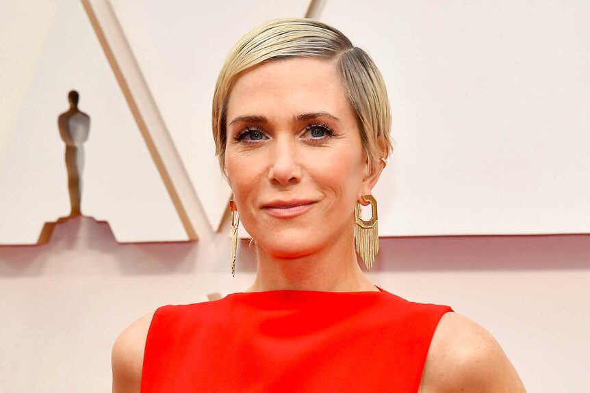 Kristen Wiig with blonde short hair and a red top at the 92nd Annual Academy Awards.