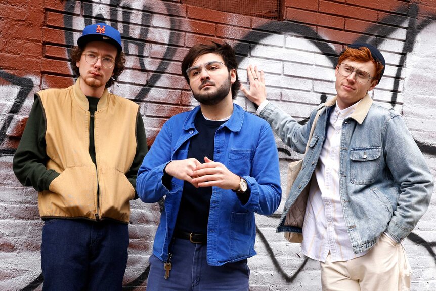 Martin Herlihy, John Higgins, and Ben Marshall posing while leaning against a brick wall during the PDD: Street Eats sketch.