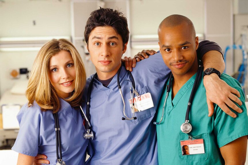 Dr. Elliot Reid, Dr. John Dorian, and Dr. Christopher Turk posing together and smiling in scrubs.