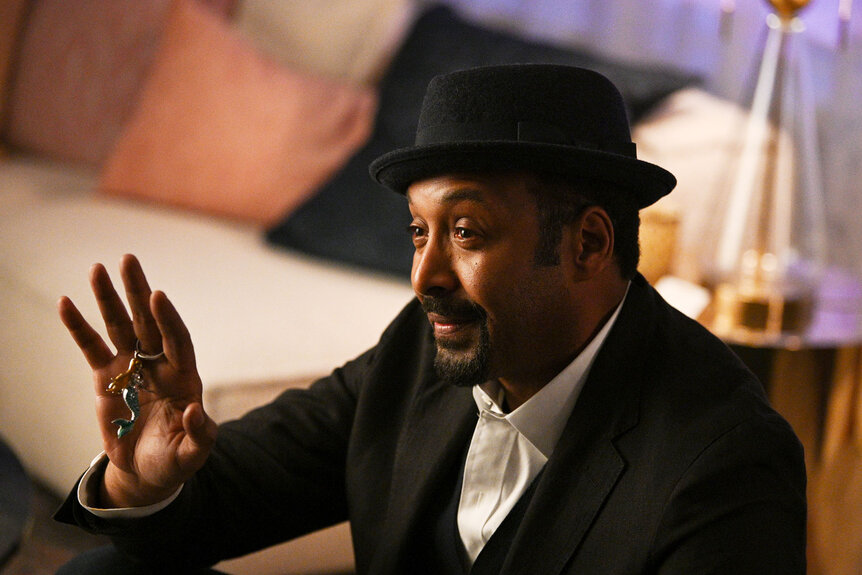 Alec Mercer (Jesse L. Martin) holds his hand up while speaking