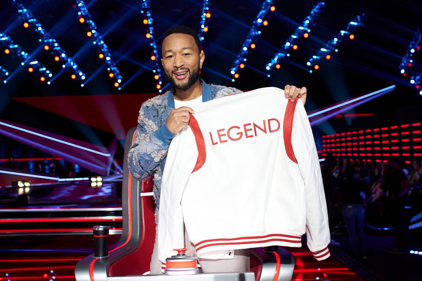 John Legend holds up his team merch
