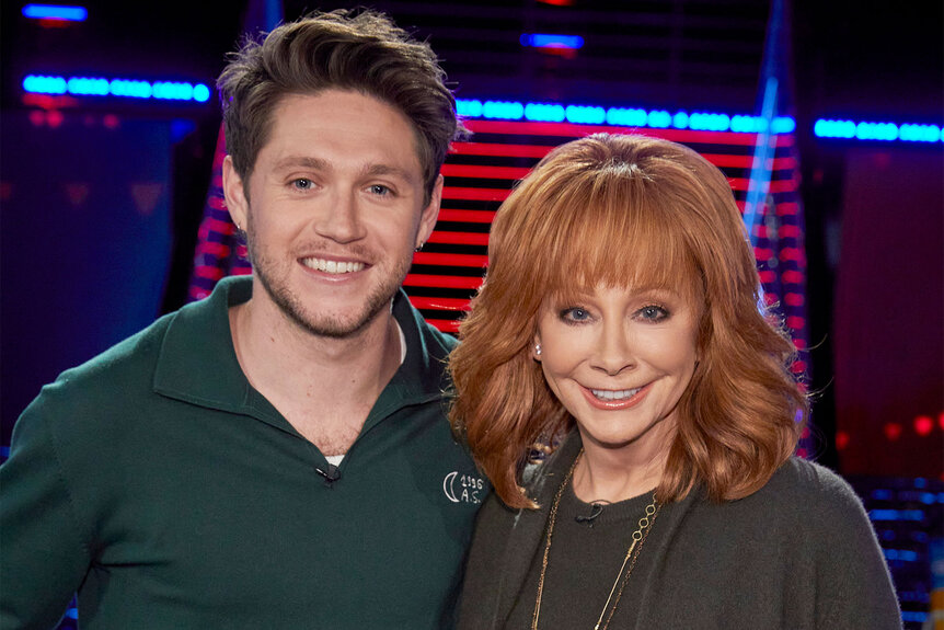 Niall Horan and Reba McEntire smile and pose for the camera on the set of The Voice