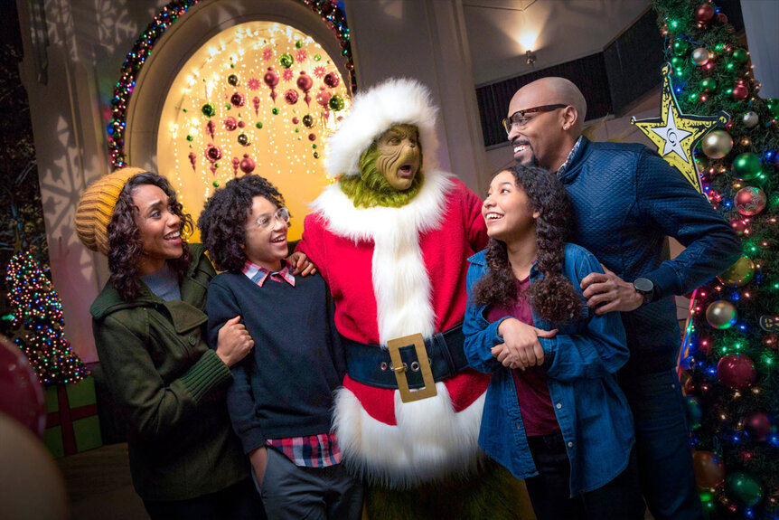 The Grinch stands with four people around him smiling