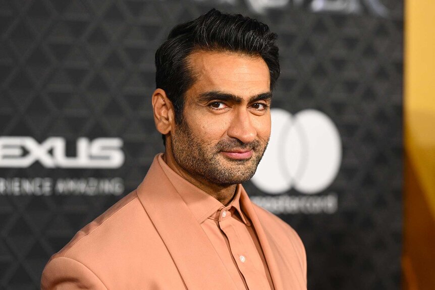 Kumail Nanjiani wearing a peach blazer and posing at the premiere of Marvel Studios Black Panther: Wakanda Forever.