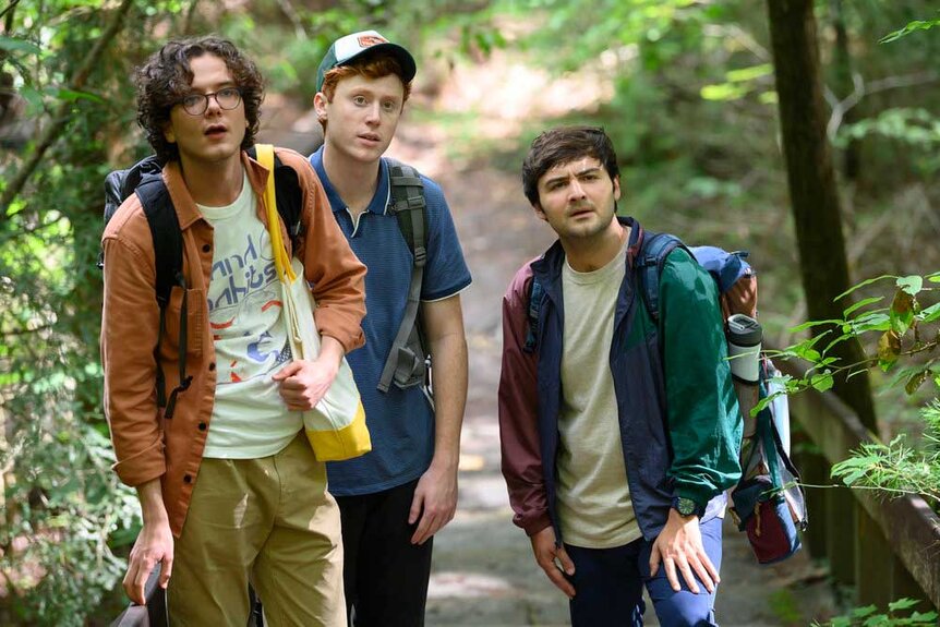 Martin, Ben, and John walking together in the forest along a path.