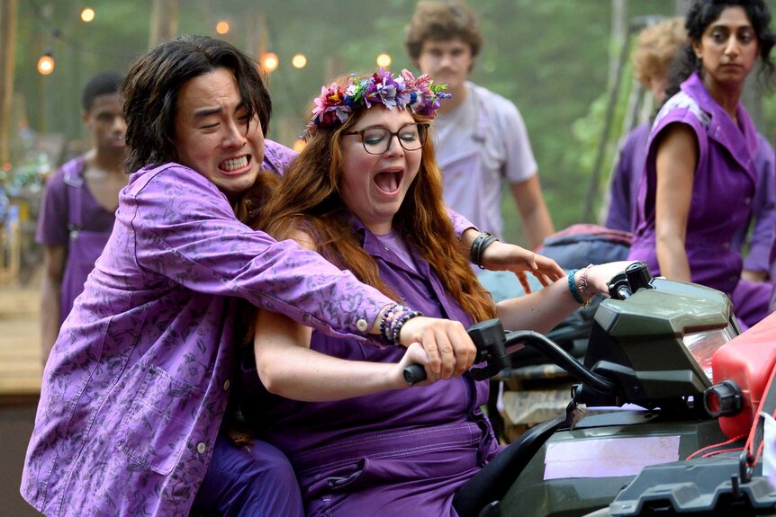 Deetch Nordwind and Lisa wearing matching purple outfits and sitting on top of a motorbike.