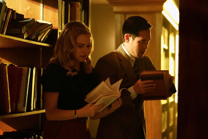 Hannah Carson and Dr. Ben Song next to each other and looking through books at a library.