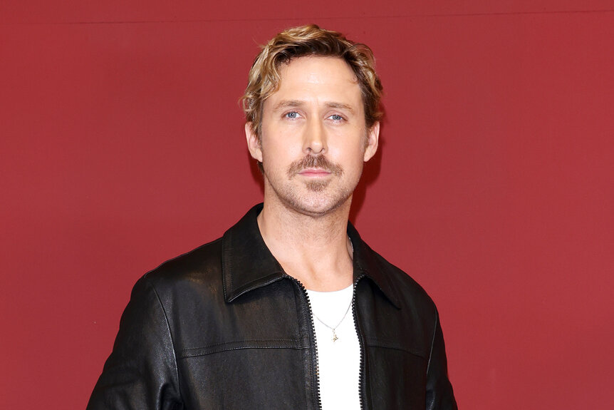 Ryan Gosling stands in front of a red background at the Gucci Ancora show