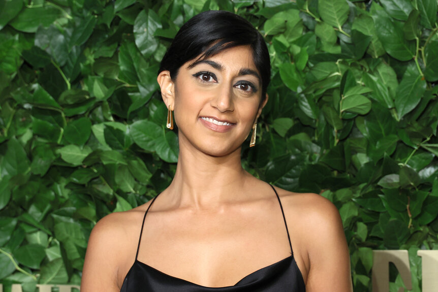Sunita Mani smiles in front of a live plant wall