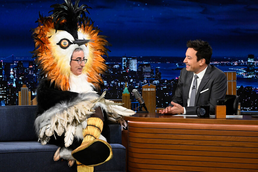 John Oliver being interviewed by Jimmy Fallon on the Tonight Show