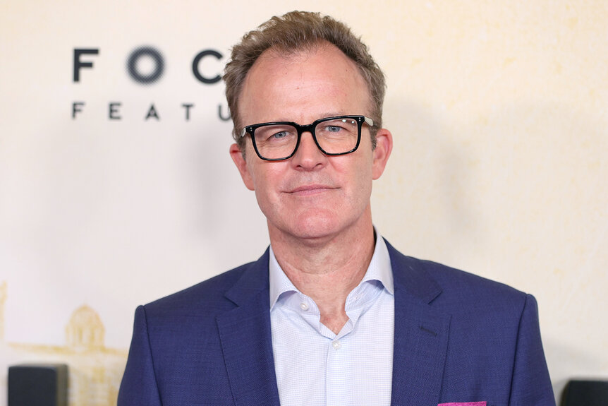 Tom McCarthy wears a blue suit and glasses at an event for his film