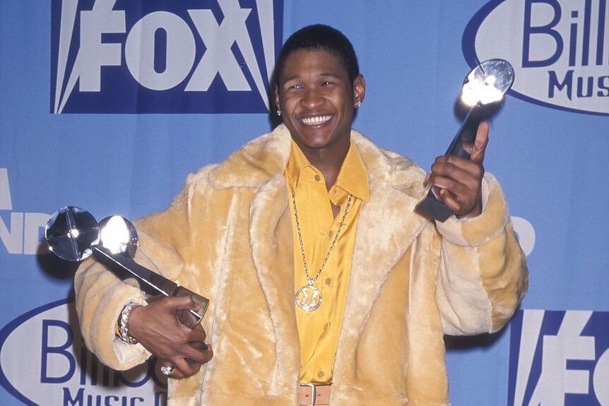 Usher smiles for photos while holding his two Billboard Music awards