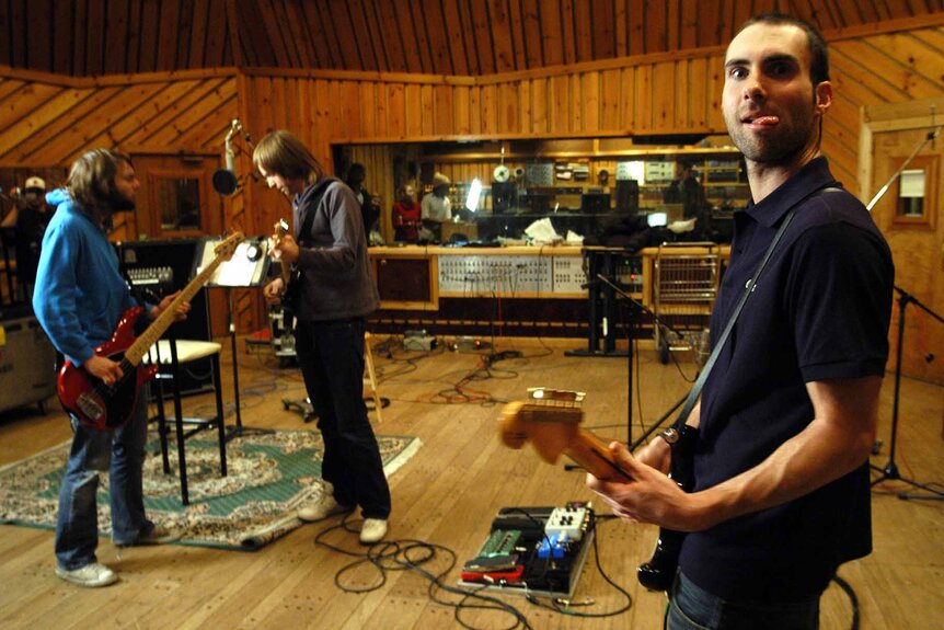 Mickey Madden, James Valentine, and Adam Levine play guitars in a recording studio.